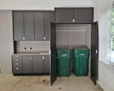 an empty garage with two trash cans in the middle and one green bin on the other side