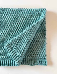 a blue knitted blanket sitting on top of a white table