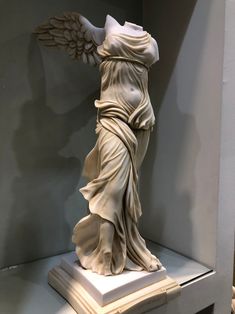 a white statue with wings on display in a room