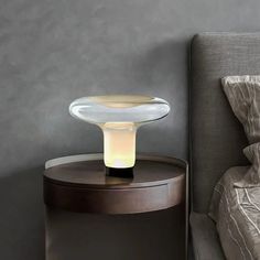 a table with a lamp on it next to a bed