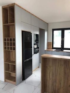 an empty kitchen with wooden cabinets and black refrigerator freezer next to it's open shelves