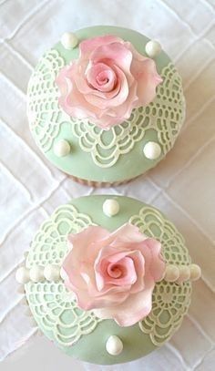 two cupcakes decorated with pink roses on top of green doily and white polka dots