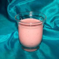 a glass filled with pink liquid sitting on top of a blue cloth