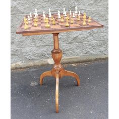 a wooden chess set sitting on top of a table next to a gray brick wall