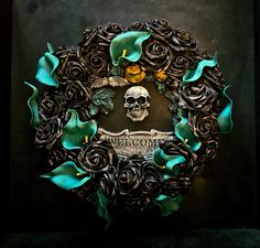 a skull surrounded by roses and leaves on a black background with the word welcome written below it