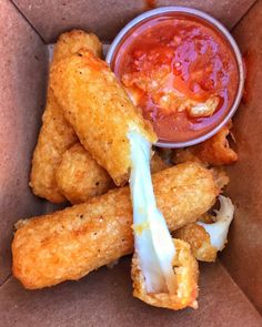 some fried food in a box with ketchup and sauce