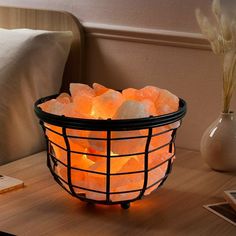 a basket filled with glowing rocks on top of a wooden table next to a pillow