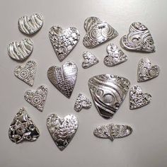 silver hearts are arranged on a white surface