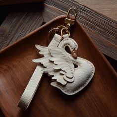 a keychain shaped like an angel with wings on it sitting on top of a wooden tray