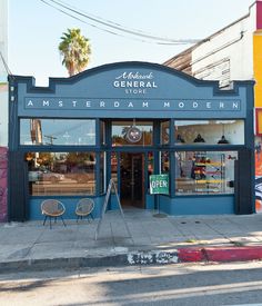 an empty street corner with a store front and chairs on the sidewalk in front of it