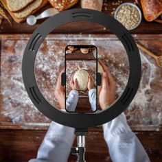 a person taking a photo of bread on a wooden table with a camera in front of them