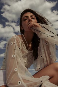 a woman is sitting on the ground with her hands to her face and looking up