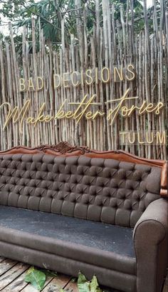 a couch sitting on top of a wooden floor in front of a bamboo fence with words above it