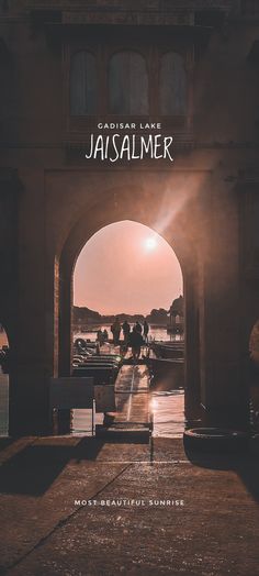 an arch leading into the distance with people walking under it in front of a building