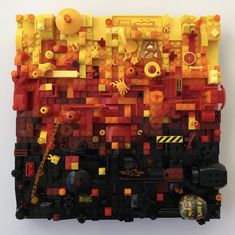 a piece of art made out of legos on a white surface with yellow and red colors