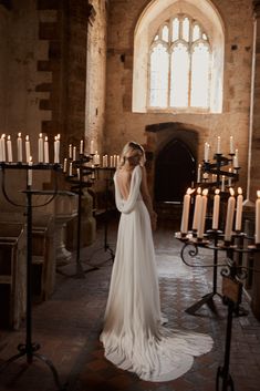 a woman in a wedding dress standing next to many candles