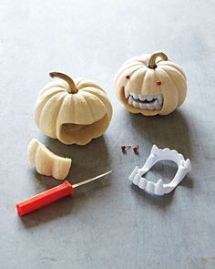 two carved pumpkins are sitting next to a pair of scissors