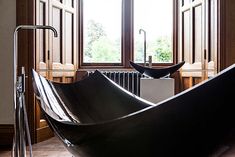 a bathtub sitting in front of a window next to a radiator and towel dispenser