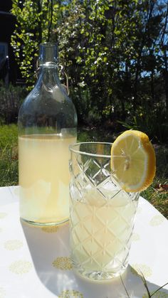 a pitcher and glass sitting on top of a table next to a lemonade bottle