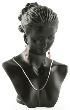 a black mannequin with a necklace and earrings on it's head, against a white background