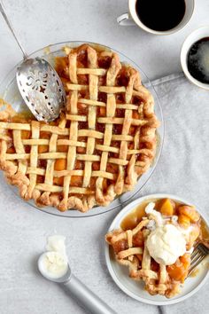 an apple pie with whipped cream on top and two cups of coffee next to it