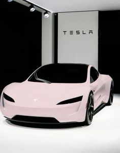 a pink car is parked in front of a white sign that says tesla on it