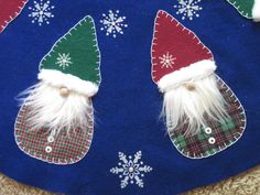 two santa hats on top of a blue christmas stocking with snowflakes around them