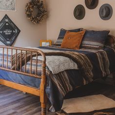 a bed sitting on top of a wooden floor next to a wall with pictures above it