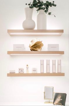 two shelves with books and vases on them in a white room, one is empty