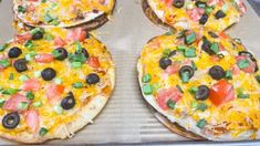 four pizzas sitting on top of a pan covered in cheese and toppings