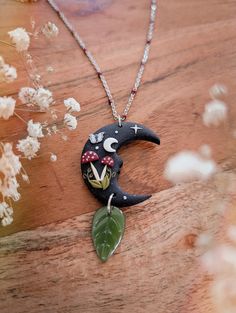 a necklace with a black and white face sitting on top of a wooden table next to flowers