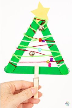 a hand holding a small christmas tree made out of popsicle sticks