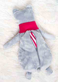 an elephant stuffed animal with a red neck tie laying on a white fur covered floor