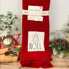 a red blanket sitting on top of a wooden table next to potted plants and other decorations