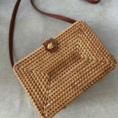 a wicker purse sitting on top of a white table next to a brown strap