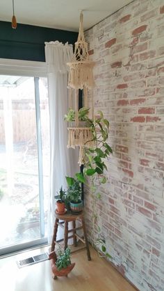 a room with a brick wall and some plants on the floor next to a window