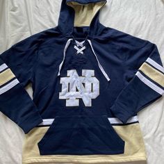 Navy, White And Gold Notre Dame Fighting Irish Lace Up Pullover Hockey Hoodie, Size Men’s Medium. I Love The Embroidered Nd Logo Design! Like New, Never Worn! Winter College Top With Drawstring Hood, Collegiate Winter Tops With Drawstring Hood, Casual Blue Tops For Winter, Collegiate Winter Top With Drawstring Hood, Hooded Tops For Game Day In Winter, Hooded Winter Tops For Game Day, Crew Neck Tops With Double-lined Hood For College, Winter Fan Apparel Top With Drawstring Hood, Blue Tops With Drawstring Hood For College