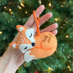 a hand holding an ornament shaped like a fox