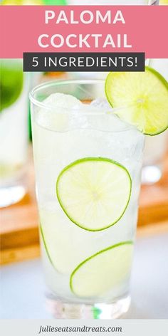 a close up of a drink in a glass with limes on the rim and another beverage behind it