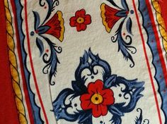 a red table cloth with blue, yellow and white designs on the border is shown