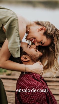 a man kissing a woman on the cheek while standing next to a body of water