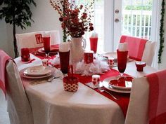 the table is set with red and white dishes, cups, and napkins on it