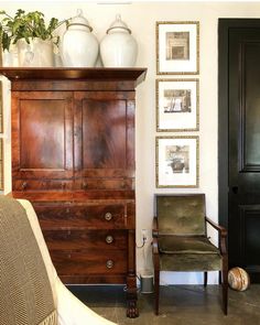 a room with a chair, dresser and pictures on the wall