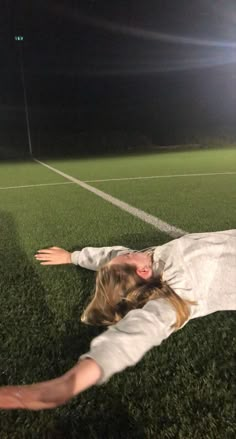 a woman laying on top of a soccer field