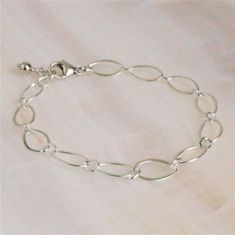 "Sterling Silver Long Loop Layering Bracelet Beautiful sterling silver long loop layering bracelet finished with a sterling silver lobster claw clasp and completed with sterling silver bead. This bracelet 7\" long and is created with 925 sterling silver material and not made with plated materials. This bracelet will arrive in a box tied with a ribbon perfect for gift giving. Also, included will be a polish pad, anti-tarnish bag with an anti-tarnish tab for storing. Please read my policies before Simple Handmade Silver Bracelets, Simple Handmade Silver Bracelet, Simple Oval Silver Jewelry, Simple Sterling Silver Chain Bracelet For Everyday, Everyday Simple Sterling Silver Chain Bracelet, Adjustable Sterling Silver Charm Bracelet Modern Style, Sterling Silver Bracelets With Simple Design, Everyday Sterling Silver Bracelets With Simple Design, Delicate Silver Charm Bracelet With Adjustable Chain