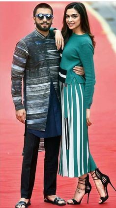 a man and woman standing next to each other on a red carpeted area, posing for the camera