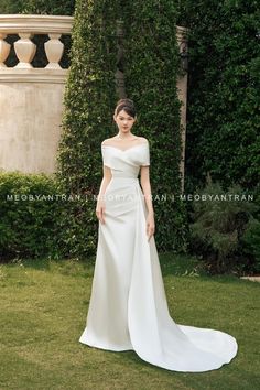 a woman in a white wedding dress standing on the grass