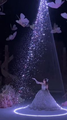 a woman in a white dress is standing under a tree with butterflies flying around her