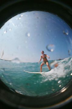 a person riding a surfboard on top of a wave in the ocean through a fish eye lens