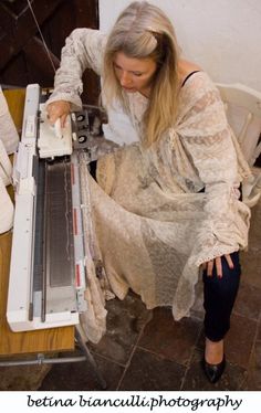 a woman is using a machine to cut fabric